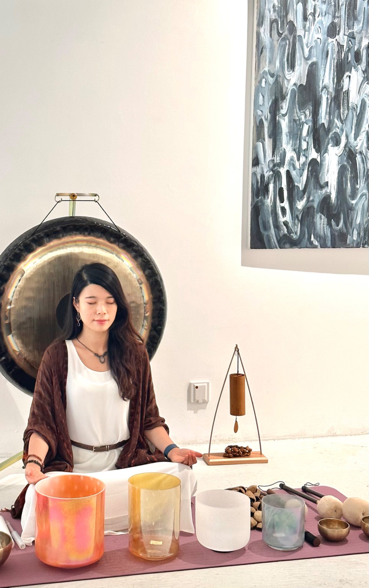 Helen meditating behind alchemy crystal bowls and a gong