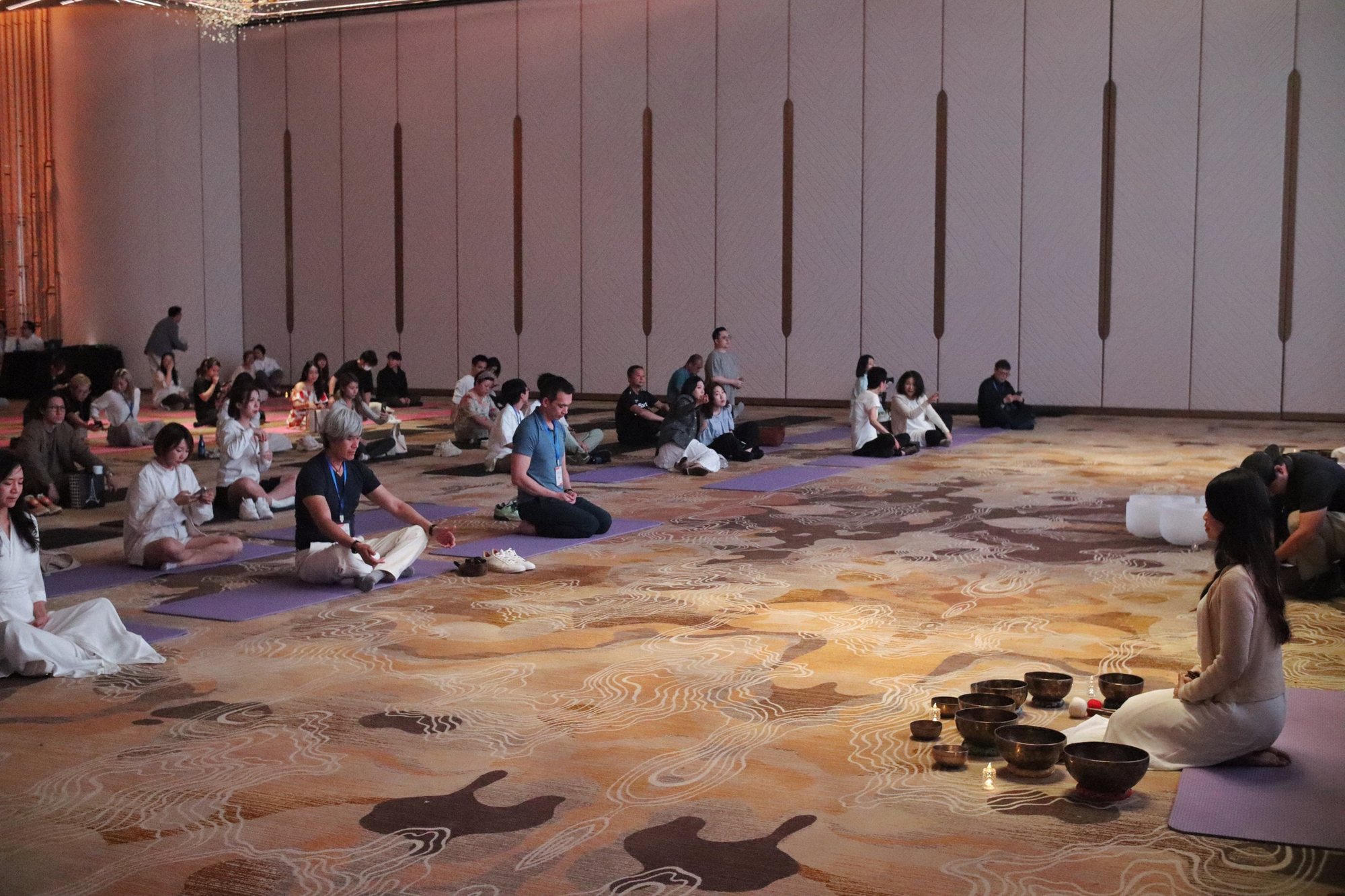 Helen leading singing bowls for guests at the Healing Arts Festival ballroom