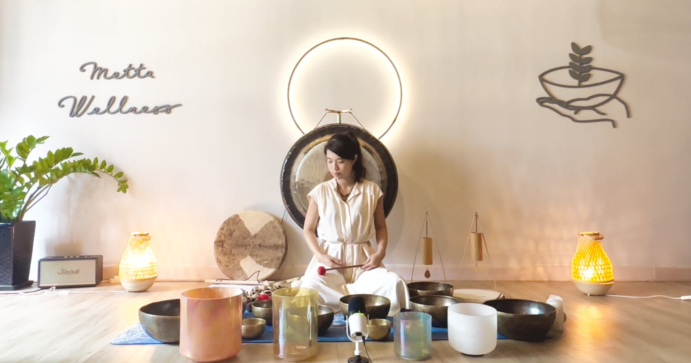 Helen Kwok playing frosted crystal singing bowls beneath a ring of light