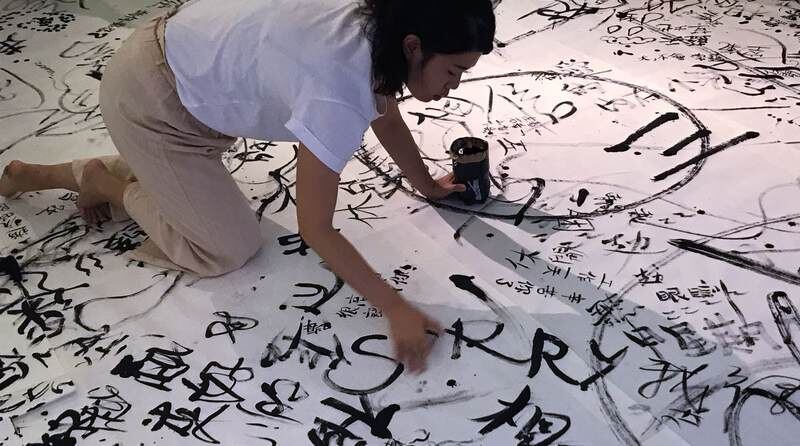 Helen performing on a floor of calligraphy