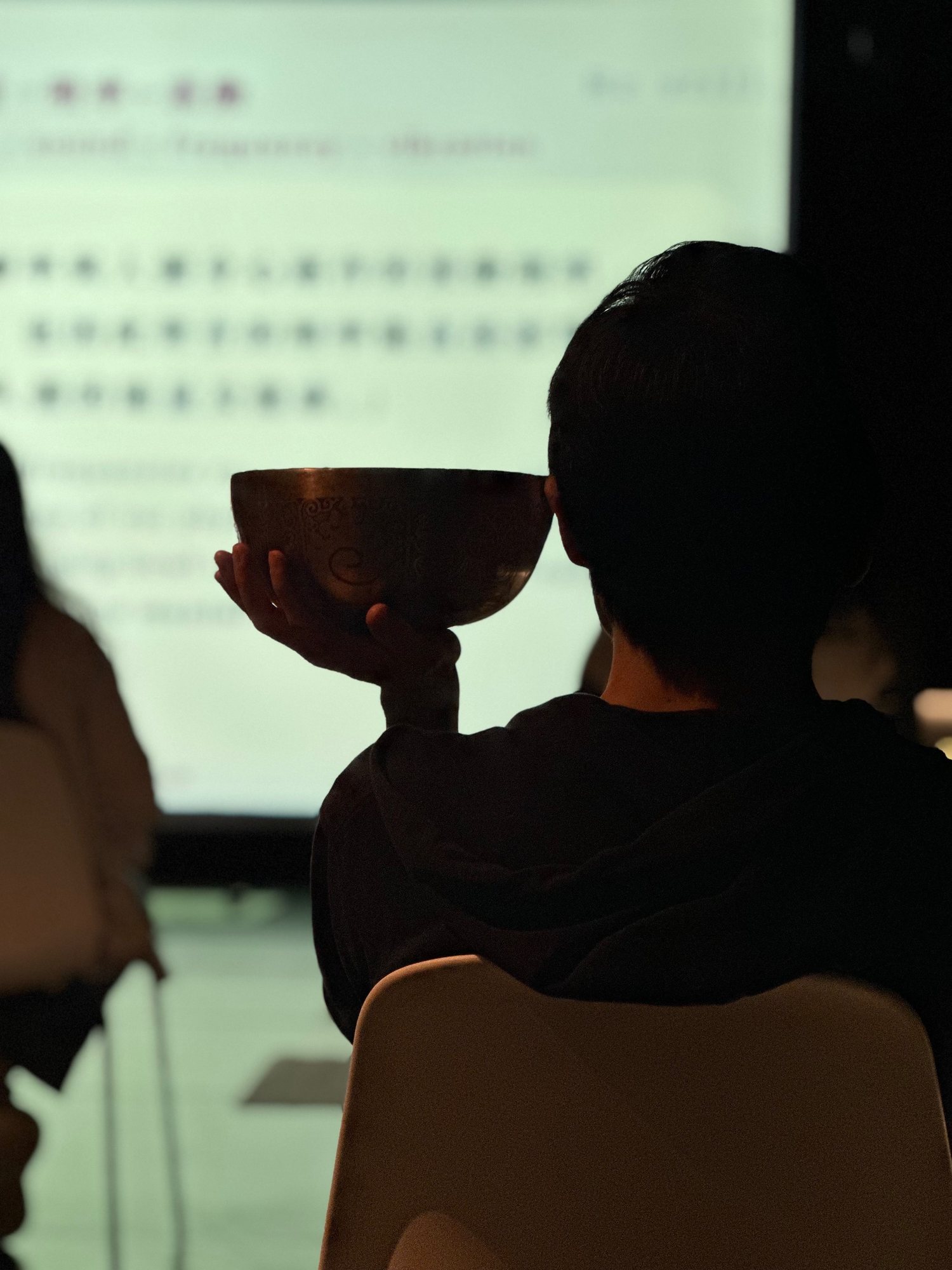 A student listening to a singing bowl held by the ear